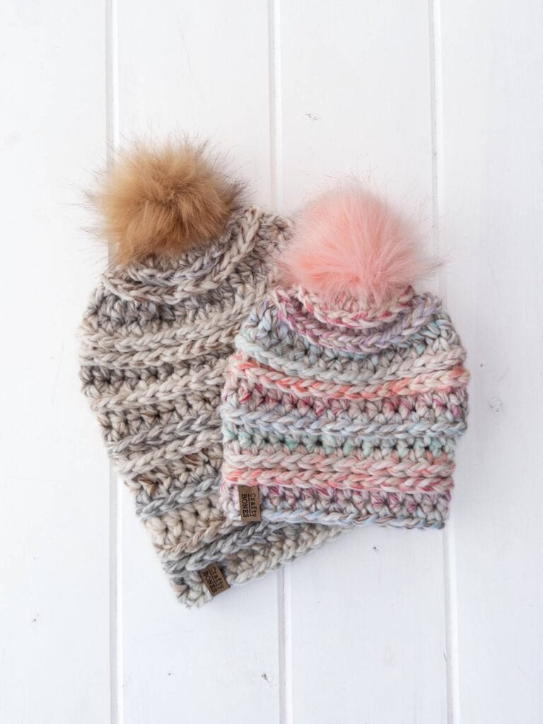 Two chunky crochet hats with pom-poms, placed on a white background.